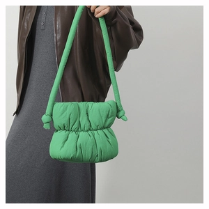 Close-up of bright green quilted puffer bucket bag with stylish knot strap detail