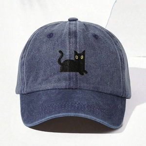 Close-up of the black cat embroidery with yellow eyes on a navy washed denim baseball cap