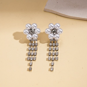 Detail of floral earrings with imitation pearls and sparkling rhinestone tassel pendants