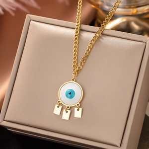 Close-up of golden evil eye necklace with three rectangular charms on a jewelry box