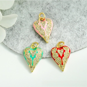 Detail view of heart-shaped enamel pendants with micro-set zircon wings in 18K gold plating
