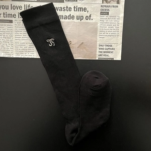 Close-up of black cotton knee-high socks featuring delicate white bow embroidery details