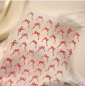 Détail des autocollants pour ongles avec nœuds en ruban rouge sur support adhésif