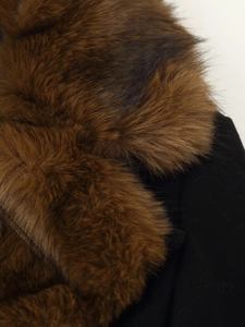 Détail du col en fausse fourrure marron foncé sur un manteau noir élégant
