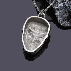 Hip hop style silver ninja face pendant with metal chain on a dark textured rock background