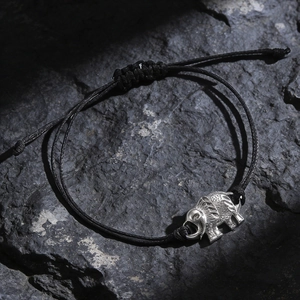 Detailed macro view of adjustable black rope bracelet with silver elephant pendant on stone