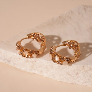 Gros plan de boucles d'oreilles créoles dorées vintage avec strass bruns et perles d'opale