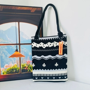 Close-up of ethnic knit tote bag featuring black and white geometric heart patterns