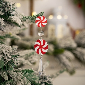Detail of red and white candy Christmas ornaments hanging on a snowy festive tree branch