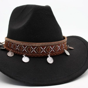Detail of black felt cowboy hat featuring ethnic embroidery and vintage coin pendants