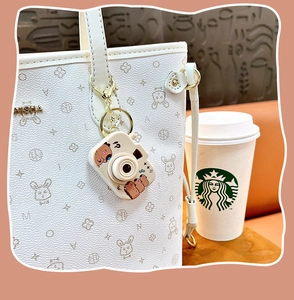 Détail d'un joli charm de sac caméra Capybara sur un sac à main blanc élégant