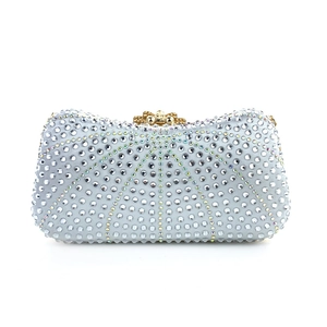 Close-up of sparkling light silver blue evening clutch bag with dense rhinestones and gold clasp