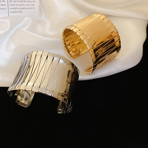 Detailed view of wide open cuff bracelets with vertical ribbed texture in gold and silver
