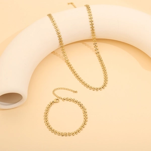 Artistic display of gold heart leaf chain necklace and bracelet set on a beige background