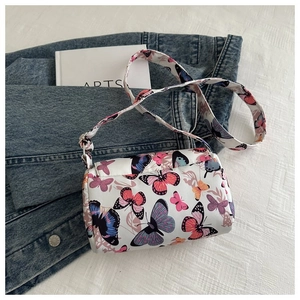 Detailed top view of cylinder crossbody bag with colorful butterfly prints on white canvas
