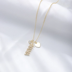 Detail of gold MAMA necklace with zircon pendant and heart charm on white silk