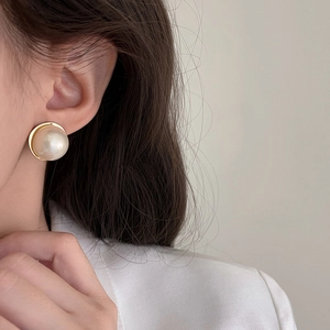 Elegant French style round pearl stud earrings with gold base worn by a female model