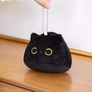 Gedetailleerd zicht op een zwarte pluche kattenkop sleutelhanger met gele borduursels