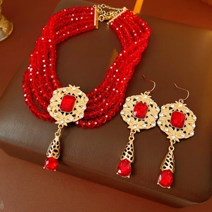 Macro view of vintage beaded necklace and drop earrings with red crystal pendant