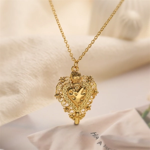 Detail of a vintage golden heart-shaped locket with ornate baroque carvings on beige fabric