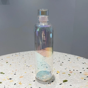 Macro shot of iridescent glass water bottle with time markers on terrazzo surface