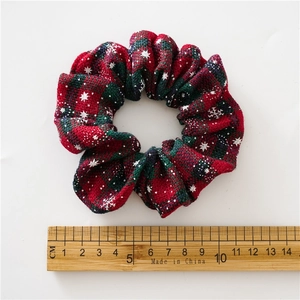 Christmas red and green plaid scrunchie with snowflake pattern shown with a size ruler