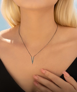 Close-up of a punk V-shaped pendant necklace with blue stones on a black chain