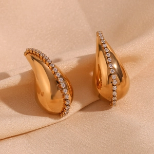 Détail de boucles d'oreilles goutte d'or avec chaîne de zircons sur soie champagne