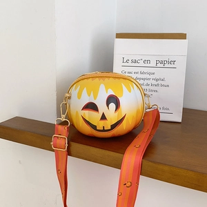 Detail of pumpkin crossbody bag featuring a smiling face and gradient orange color
