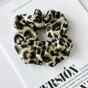 Close-up of a dark green leopard print satin scrunchie displayed on a fashion magazine