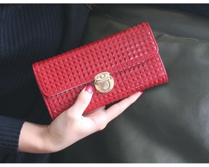Gros plan du grand portefeuille rouge avec texture géométrique et fermoir doré rotatif