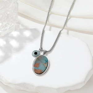 Retro natural stone pendant necklace with silver chain on a white textured stone surface
