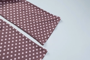 Détail du tissu violet foncé à pois roses avec coutures précises sur l'ourlet du haut