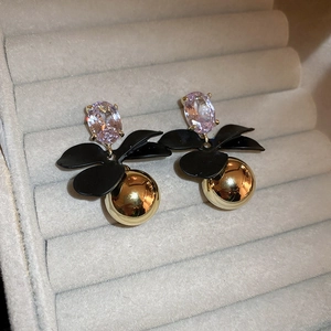 Detailed macro view of retro geometric earrings featuring a pink crystal and black flower