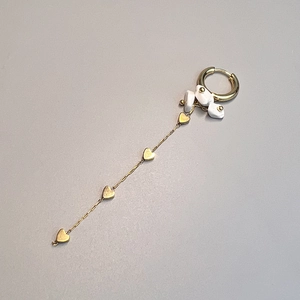 Detail of gold drop earring with white natural stones and four heart charms on a long chain