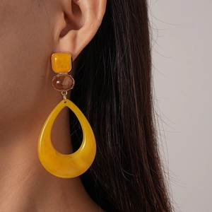 Close-up of model wearing yellow resin geometric drop earrings with amber beads