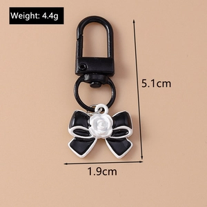 Detail view of bow pendant keychain with measurements 5.1cm length and 1.9cm width