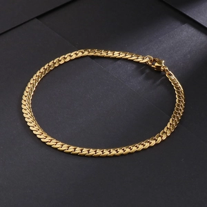 Close-up of golden stainless steel Cuban chain bracelet on dark geometric surface