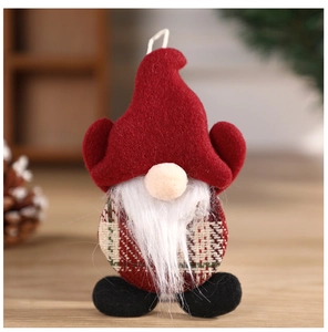 Detail of Christmas gnome ornament with red felt hat and plaid fabric body on wooden table