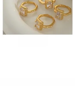 Detail of four gold adjustable rings with irregular lava texture and rectangle zircon stones