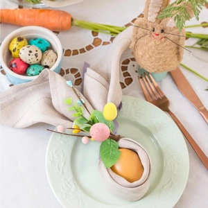 Easter bunny ear napkin ring with greenery and colorful berries on a decorative dinner plate
