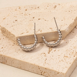 Detailed close-up of 304 stainless steel chunky silver croissant earrings on beige stone