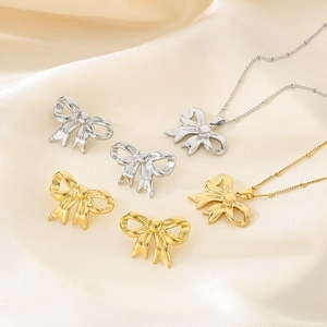 Detailed set of gold and silver hollow bow necklaces and earrings on beige silk fabric
