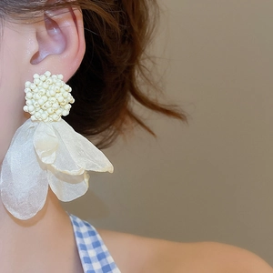 Macro detail of creamy white beaded stud with layered chiffon petal drop on female model