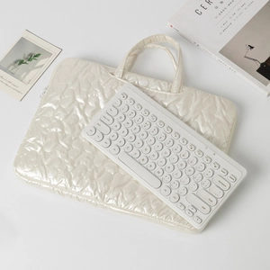 Detail of pearl white laptop sleeve featuring 3D heart-shaped quilted pattern and texture