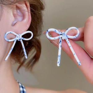 Vue détaillée des boucles d'oreilles nœud à motif d'encre bleue portées sur l'oreille