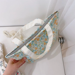 Detailed view of cream floral canvas handbag featuring a secure silver metal zipper