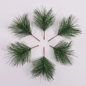 Detail view of 6 artificial green pine needles arranged symmetrically on a white background