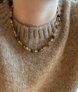 Detail of 18k gold tiger eye pea necklace layered on a soft brown mohair sweater