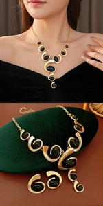 Detail of vintage gold jewelry set with oval black stones on dark velvet
